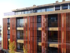 an apartment building with red vertical slats on the facade