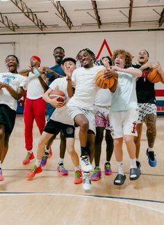 a group of young men playing basketball in an indoor court with one holding a ball