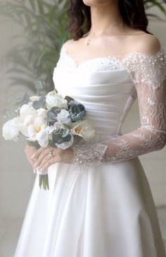 a woman in a white dress holding a bouquet of flowers