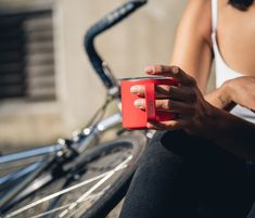 a woman sitting on the ground holding a red cup