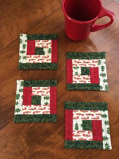 four quilted coasters sitting on top of a wooden table next to a coffee cup