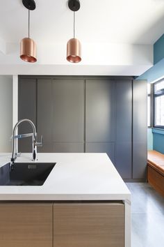 a kitchen with an island sink and two copper lights hanging from the ceiling over it