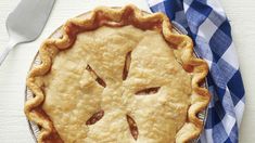 an apple pie on a blue and white checkered table cloth with a fork next to it