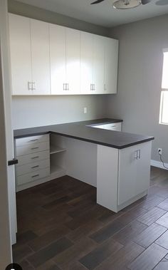 an empty kitchen with wooden floors and white cabinets