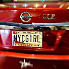 the front end of a red car with a license plate that reads new york girl giants