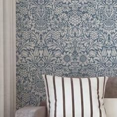 a white couch sitting next to a wall with a blue and white pattern on it