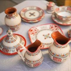 a table topped with plates and vases filled with different types of dishes on top of a white cloth covered table