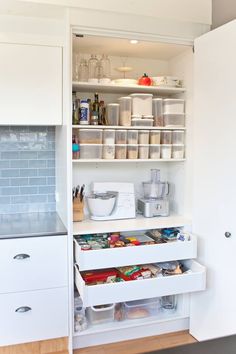 an open pantry with lots of food and containers on shelves next to a counter top