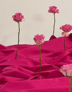 three pink roses are in the middle of a bed sheet with one flower sticking out of it