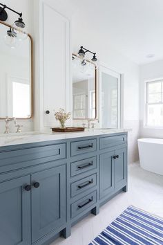 a large bathroom with blue cabinets and white walls, along with a striped rug on the floor