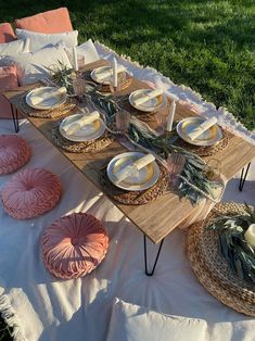 a table set up with plates, bowls and napkins for an outdoor picnic party