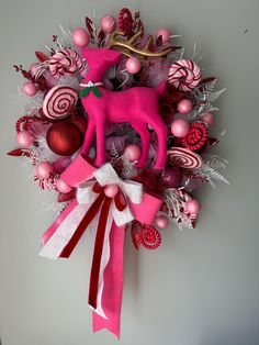 a christmas wreath with candy canes and a pink reindeer ornament hanging on the wall