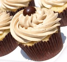 three cupcakes with white frosting and chocolate on top are sitting on a plate