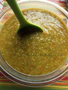 a spoon in a bowl filled with green sauce on top of a striped table cloth