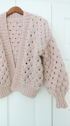 a pink sweater hanging on a white door