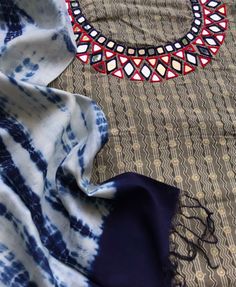 a blue and white scarf laying on top of a bed next to a round mirror