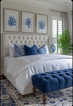 a bedroom with blue and white decor on the wall above the bed, along with a footstool