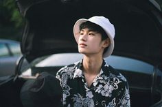 a young man sitting in the trunk of a car with his hat over his head