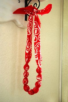 a red and white scarf hanging from a hook on a wall next to a coat rack