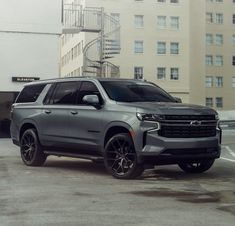 a silver chevy suburban parked in front of a building