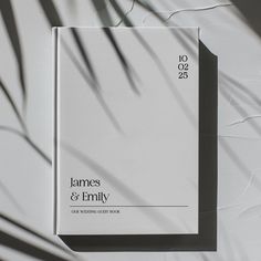 a white book sitting on top of a table next to a palm tree shadowing the wall