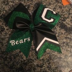 a green and black cheer bow with the letter g on it's side that says bears