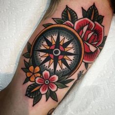 a close up of a person's foot with a compass and flowers on it