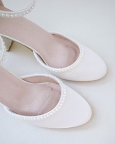 a pair of white shoes with pearls on the toe and heel are sitting next to each other