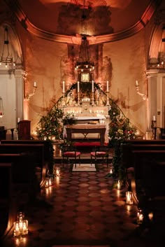 the interior of a church with candles lit on the pews and an altar in the background