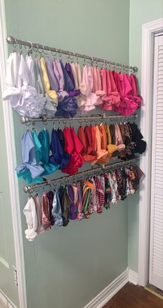 a rack with many different colored shirts hanging from it's sides in a room