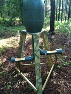 a wooden stand with a large green ball on it's top in the woods