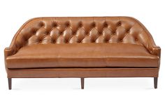 a brown leather couch sitting on top of a white floor