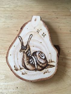 a wood slice with a snail painted on it's side and stars in the background