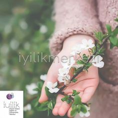 a person holding white flowers in their hands with the words iyilik on it