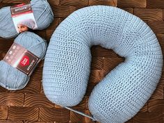 two balls of yarn sitting on top of a wooden floor next to a blue knitted pillow