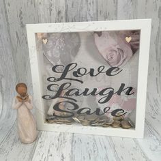 a small figurine sitting next to a white frame that says love laugh save