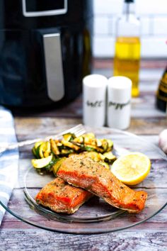 salmon, zucchini and lemons on a glass plate next to an air fryer