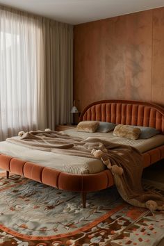 a large bed sitting in the middle of a bedroom next to a window with curtains