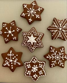 six decorated cookies are arranged on a white tablecloth with snowflakes in the middle