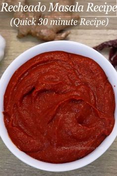 a white bowl filled with red sauce on top of a wooden table