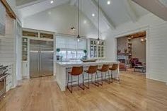 an open kitchen and living room with white walls, wood floors and vaulted ceiling beams