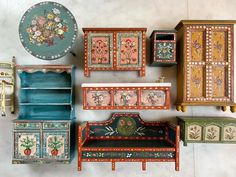 an assortment of painted furniture on display in a room with white walls and flooring