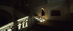 a woman is walking down the stairs in an old building with light shining on her