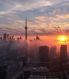 the sun is setting over a city with tall buildings and skyscrapers in the background