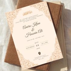 two brown and white wedding cards sitting on top of each other