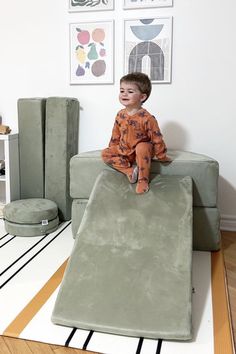 a young boy sitting on top of a green couch