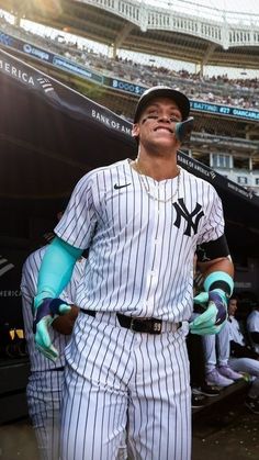 a baseball player standing in the dugout with his gloved hands on his hips