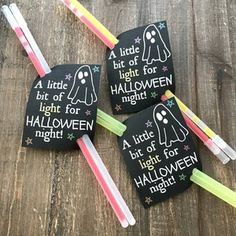 four halloween tags with glow sticks in them on top of a wooden table next to toothbrushes