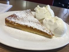 a piece of pie and ice cream on a white plate at a table with a book