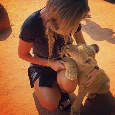 a woman holding a baby lion in her lap